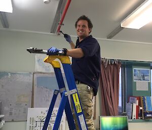 A man up a ladder with a wrench