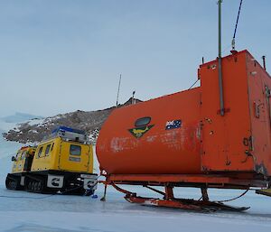 A yellow Hägglunds with a orange caravan behind