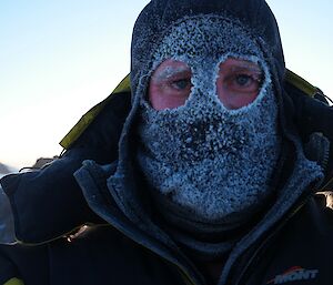 A man wearing a balaclava covered in ice
