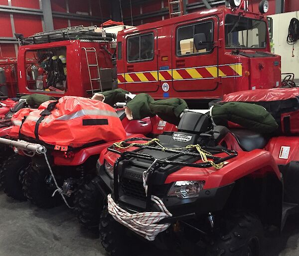 a red hagglund and 3x quad bikes with equipment bags