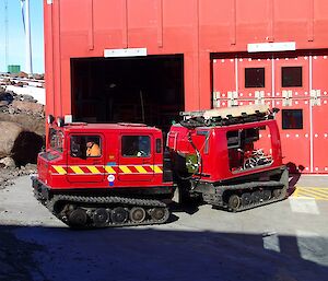 a red hagglund outside of a red shed