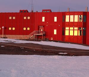 a large red shed with the sunrise reflected in its windows