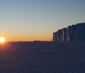 a large yellow sun setting over the sea ice