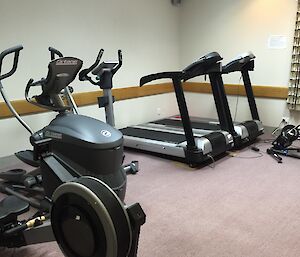 a room with treadmill, rowing machine and cycle