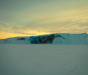 A jade berg with a sunset behind