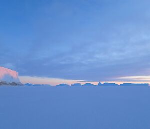 A ice berg with a sunset reflected off it