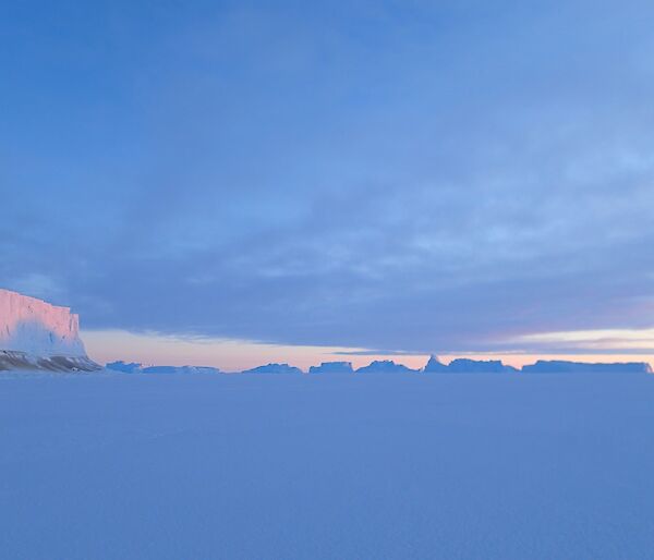 A ice berg with a sunset reflected off it