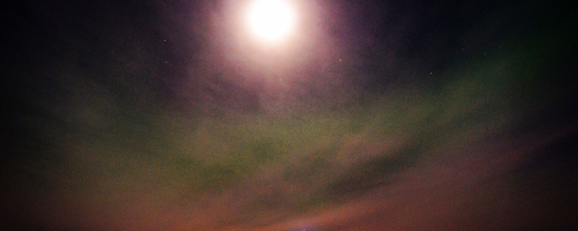 a large full moon and green aurora in the sky