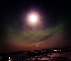 a large full moon and green aurora in the sky