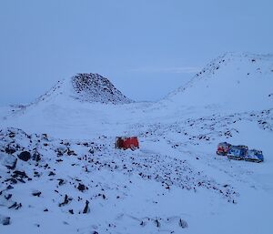 A small orange hut in the middle of hills