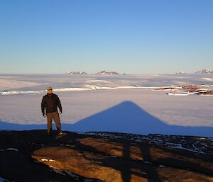 A man on top of a hill with a mountain range in the background