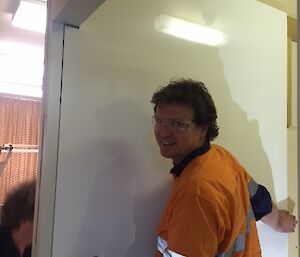 A man holding a piece of bathroom wall sheeting