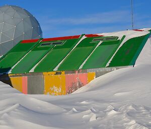 a hut made of multicoloured yellow and pink panels with a green roof