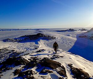 a man walking up the ridge of a hill