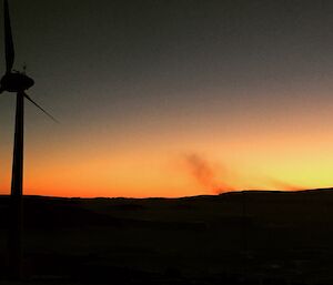 blowing snow in front of a orange sunrise