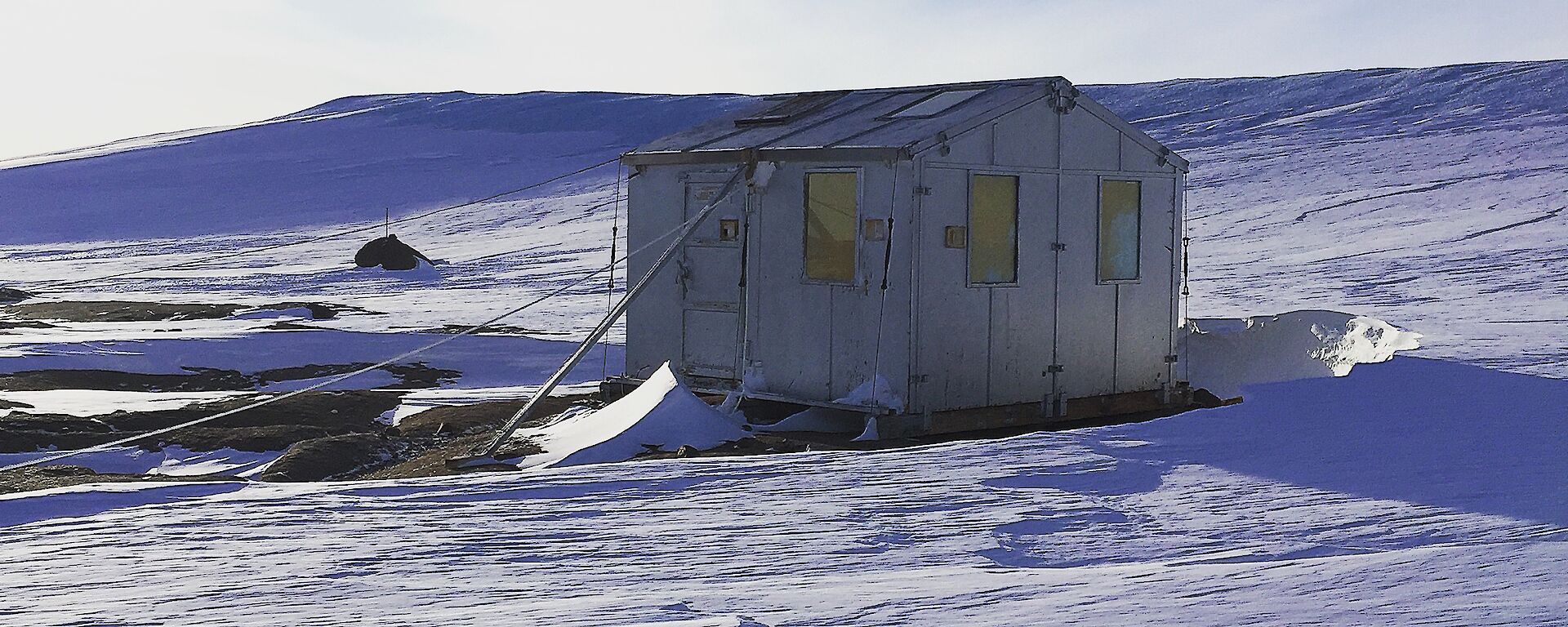 a small wooden hut in front of a glacier