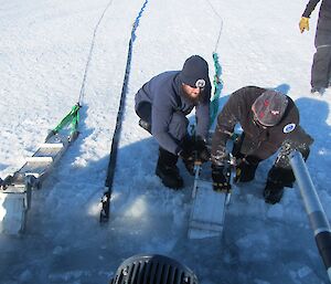 two men inserting ramps into the sea ice