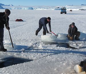 three men removing chunks of ice to make room for the hagglund