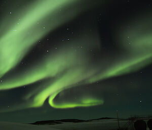 Green aruora with snow and large round containers in the foreground