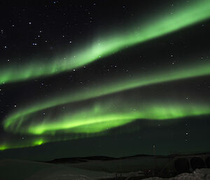 Green ribbon aurora with a pile of snow in the foreground