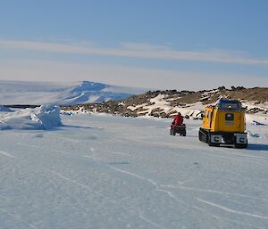 A yellow hagg and a quad bike driving on the sea ice