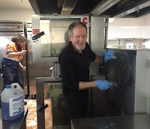 a man scrubbing stainless steel deep fryer in the kitchen