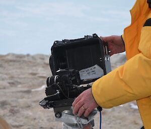 a DSLR camera in a protective black case with an expeditioner fixing it