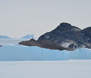 A view across sea ice to ice bergs and an island