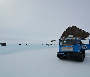 A blue hagglund with a back drop of Mountains
