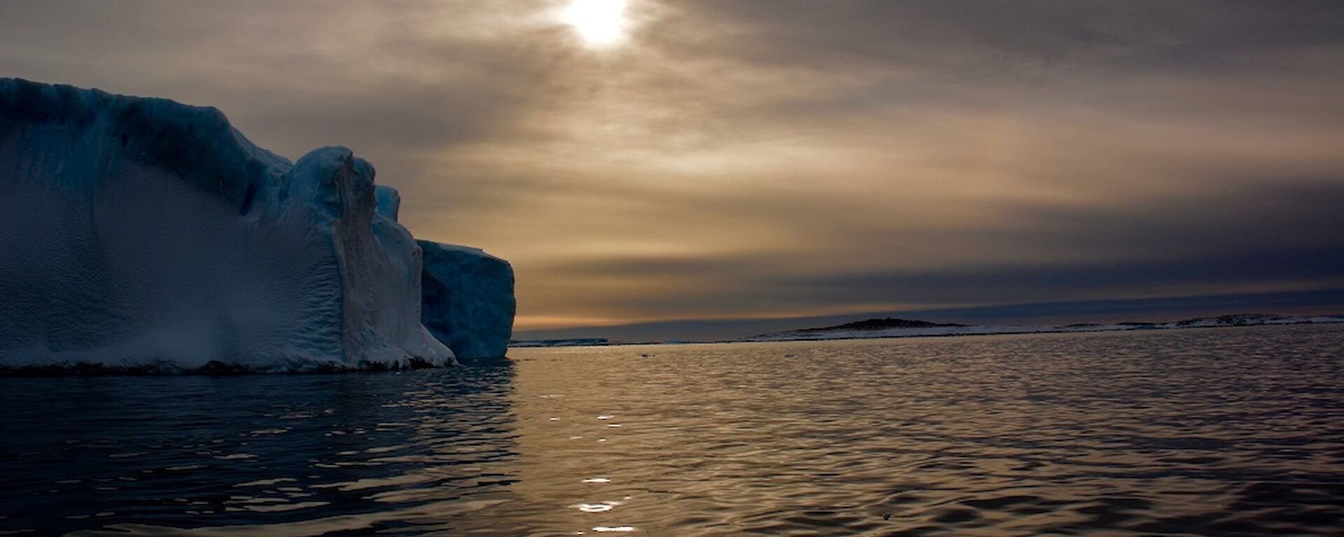 A small iceberg with weak sunlight backlighting it