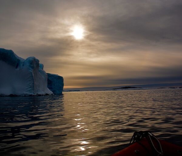 A small iceberg with weak sunlight backlighting it