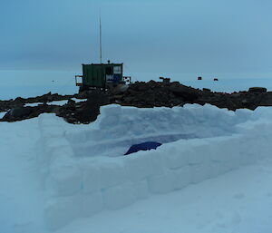 The snow block wall built to keep the wind from his bivvy