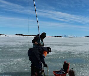 Tony Harris and Ben Newport use a camera attached to a long pole to locate the tide gauge casing and remove the plug