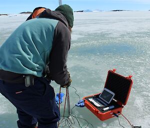 Expeditioners carefully position the tide gauge in the ice