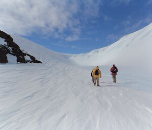 Three expeditioners walking around a wind scoop near Mt Henderson