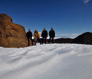 Four men standing in front of David Range with ice in front of them.