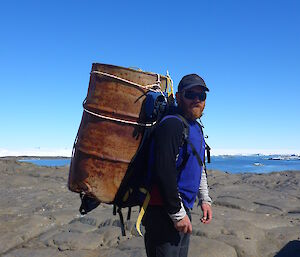 Expeditioner with an empty fuel drum strapped to his back.