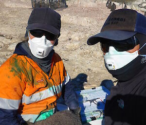 Two penguin researchers on Bechervise Island wearing full PPE while tagging Adelie penguins chicks