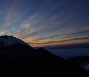 an orange sunset behind Mt Henderson