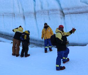 four expeditioners stand in front of a 10 metre wall of ice