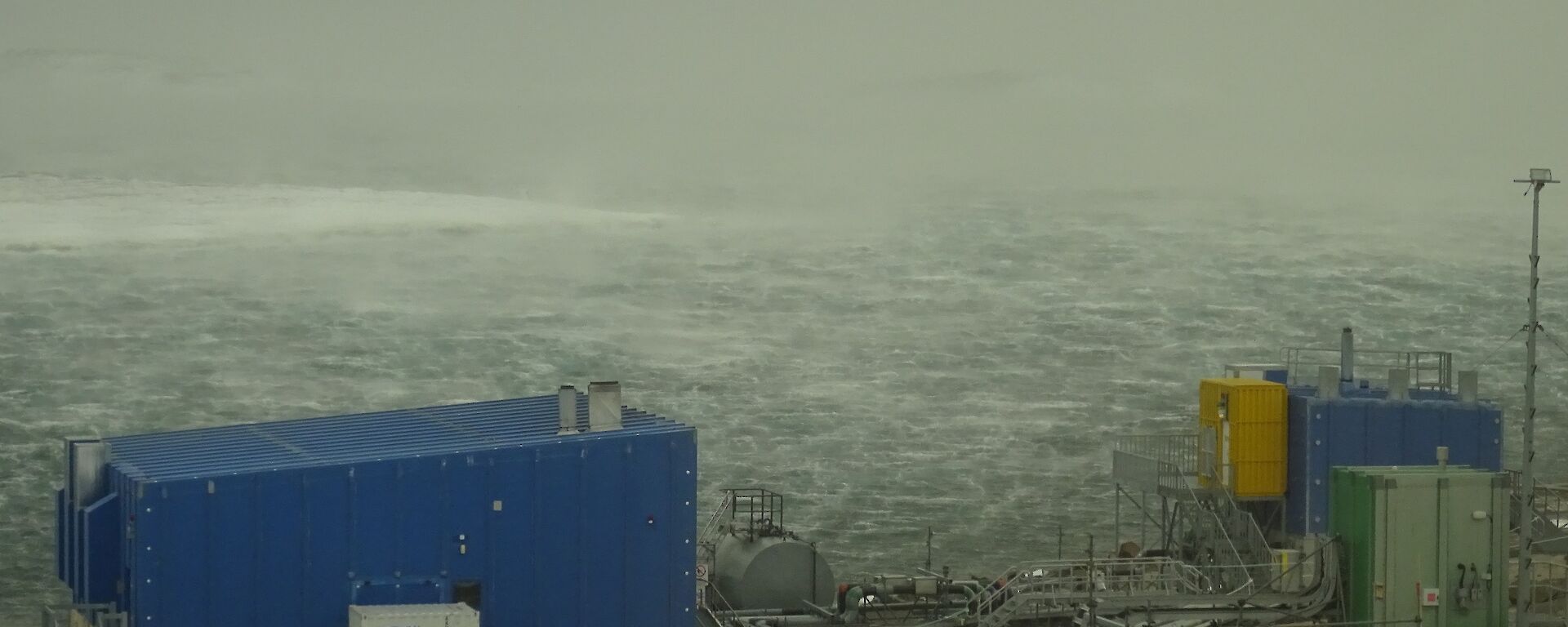 a windswept harbour with blue buildings in the foreground