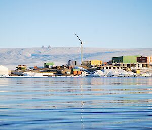 a view of Mawson Station with multi coloured buildings, a wind turbine taken over a harbour