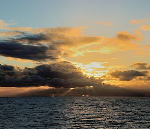 a sunset with grey clouds over the deep blue southern ocean