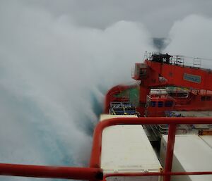 a large white wave crashes over the bow of the Aurora Australis