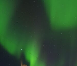 A spectacular green Aurora lights up the night sky over the wind turbine