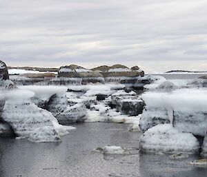 A series of rocks with frozen tide marks in stripes
