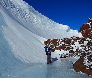 a man is standing at the foot of a rocky hill