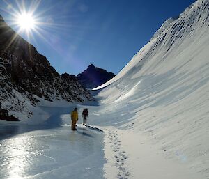 a man in a yellow jacket stands on ice ready to walk into a valley