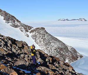 a woman is standing among rocks overlooking a white plateau