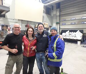 three men and women stand in a workshop